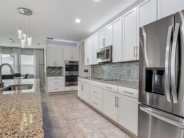 12313 Prairie Plantation Way, Orlando, FL 32824 - kitchen with stainless steel appliances, a sink, decorative backsplash, light stone countertops, and decorative light fixtures