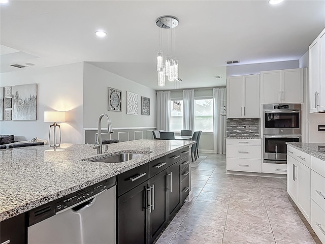 12313 Prairie Plantation Way, Orlando, FL 32824 - kitchen featuring stainless steel appliances, a sink, light stone countertops, dark cabinetry, and white cabinetry