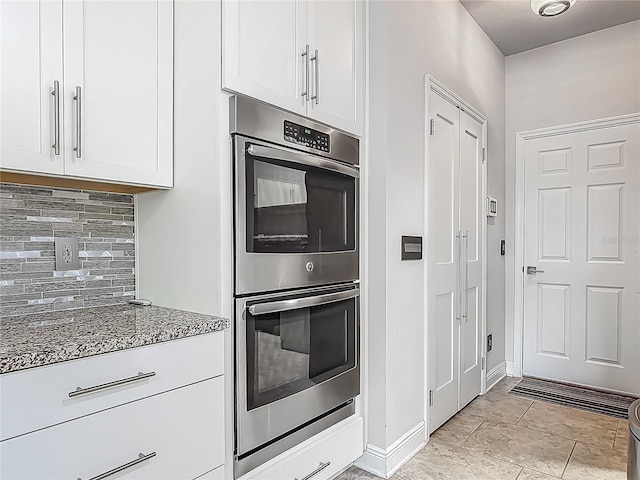 12313 Prairie Plantation Way, Orlando, FL 32824 - kitchen with double oven, dark stone countertops, decorative backsplash, white cabinets, and baseboards