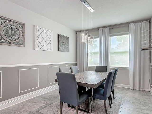 12313 Prairie Plantation Way, Orlando, FL 32824 - dining area featuring a textured ceiling, wainscoting, and light stone finish floors