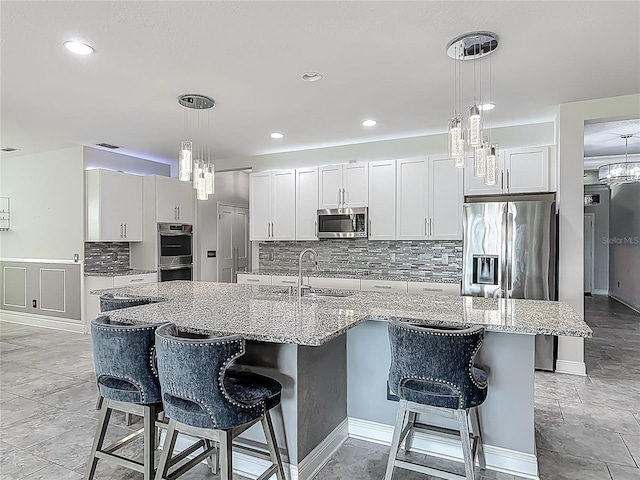 12313 Prairie Plantation Way, Orlando, FL 32824 - kitchen featuring appliances with stainless steel finishes, a sink, backsplash, a kitchen breakfast bar, and a kitchen island with sink