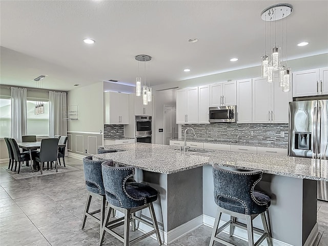 12313 Prairie Plantation Way, Orlando, FL 32824 - kitchen with appliances with stainless steel finishes, a sink, tasteful backsplash, a breakfast bar area, and decorative light fixtures