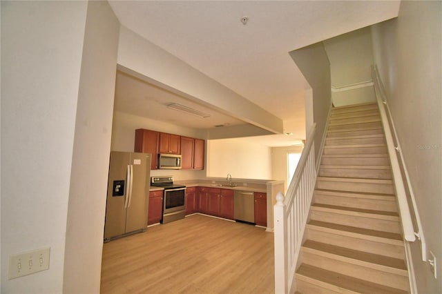 3151 Sinclair St Unit 104, Orlando, FL 32835 - kitchen featuring appliances with stainless steel finishes, a sink, light wood-style flooring, brown cabinetry, and light countertops