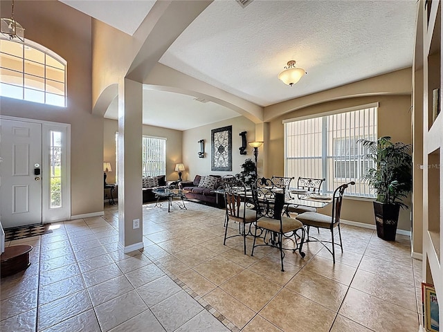 219 Rosso Dr, Davenport, FL 33837 - dining area with arched walkways, light tile patterned floors, baseboards, and a textured ceiling