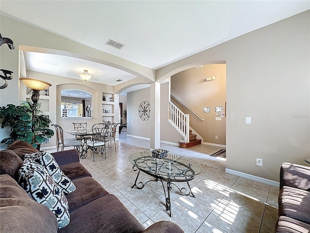 219 Rosso Dr, Davenport, FL 33837 - living room with arched walkways, stairs, tile patterned floors, baseboards, and built in shelves