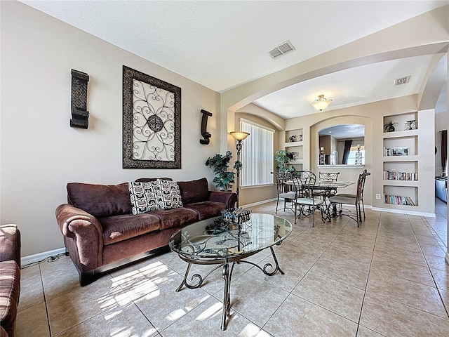 219 Rosso Dr, Davenport, FL 33837 - living area with arched walkways, baseboards, built in shelves, and light tile patterned flooring