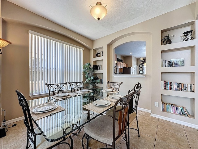 219 Rosso Dr, Davenport, FL 33837 - dining space with built in shelves, a textured ceiling, baseboards, arched walkways, and tile patterned floors