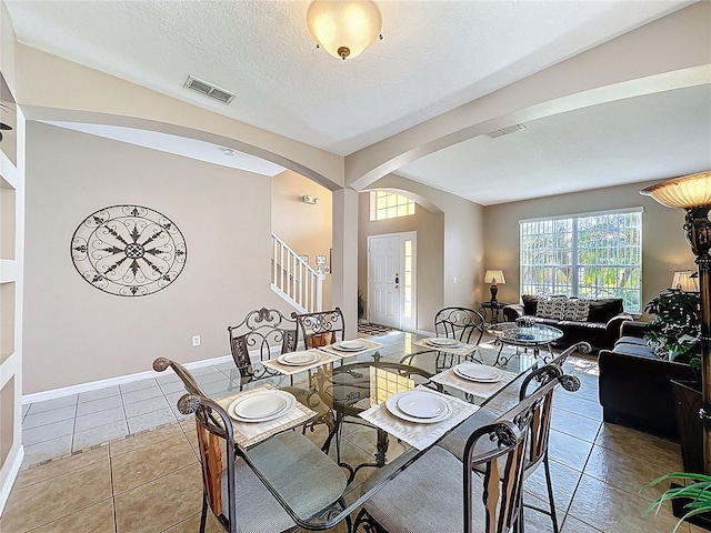 219 Rosso Dr, Davenport, FL 33837 - dining room featuring arched walkways, tile patterned floors, baseboards, and a textured ceiling