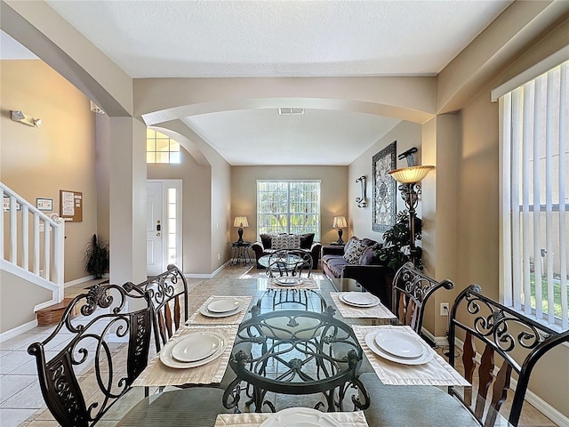 219 Rosso Dr, Davenport, FL 33837 - dining area with arched walkways, baseboards, and stairway