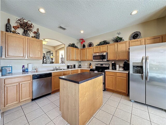 219 Rosso Dr, Davenport, FL 33837 - kitchen featuring appliances with stainless steel finishes, a sink, a textured ceiling, a center island, and light tile patterned flooring