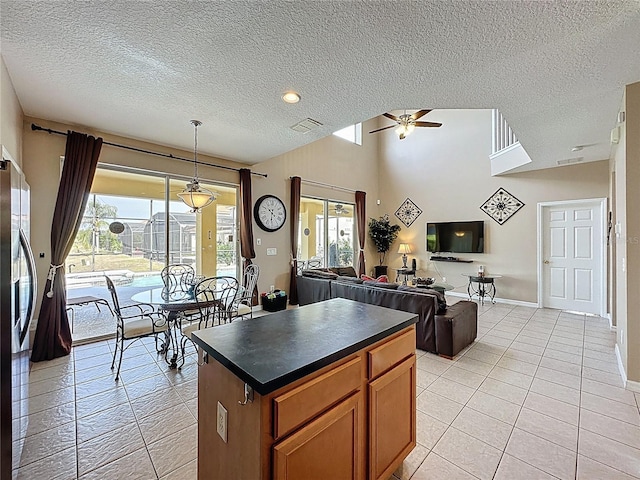 219 Rosso Dr, Davenport, FL 33837 - kitchen featuring dark countertops, a ceiling fan, a textured ceiling, light tile patterned flooring, and brown cabinets
