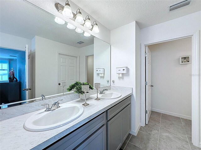 1181 Lone Palm Way, Saint Cloud, FL 34771 - bathroom featuring double vanity, a textured ceiling, tile patterned floors, and baseboards