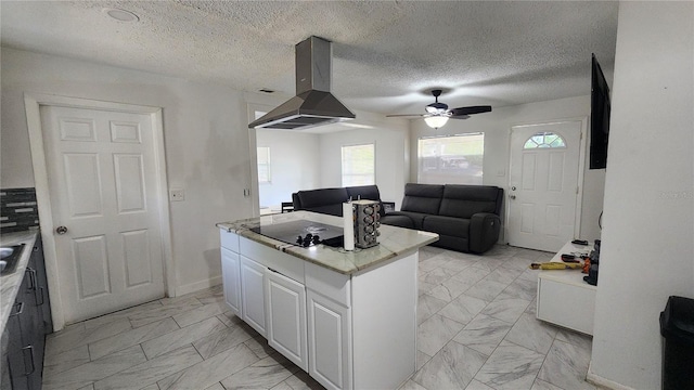 kitchen with light marble finish floors, island range hood, black electric stovetop, white cabinetry, and ceiling fan