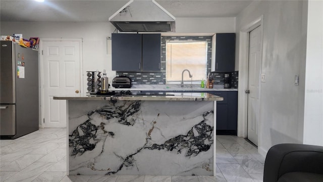 kitchen with freestanding refrigerator, custom exhaust hood, backsplash, light marble finish flooring, and blue cabinets