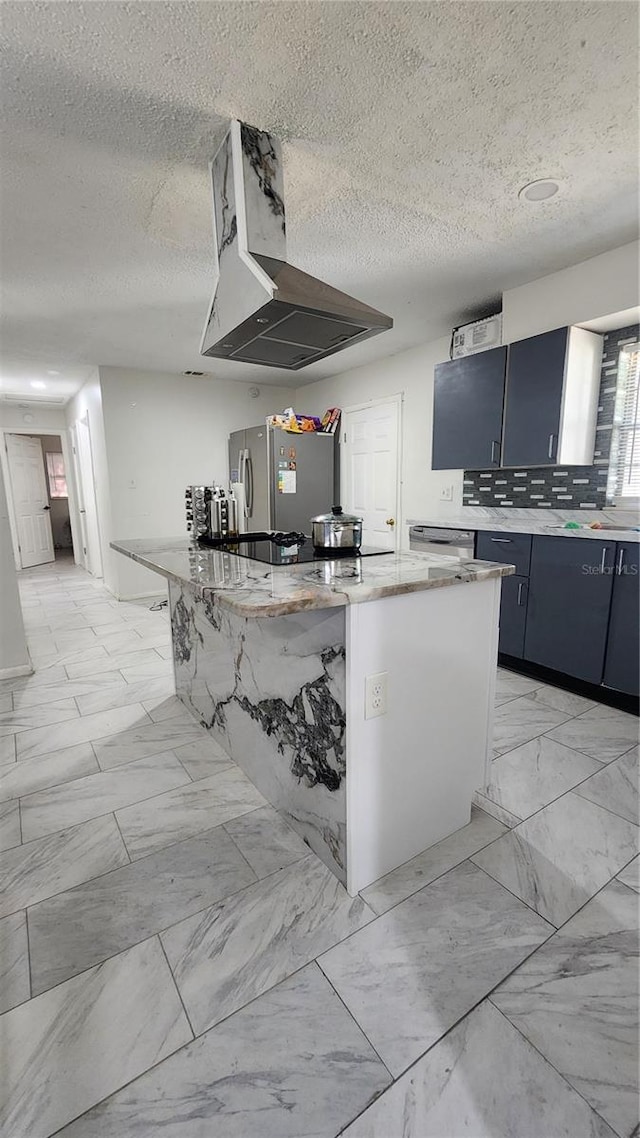 kitchen with light marble finish flooring, stainless steel appliances, a textured ceiling, a large island, and decorative backsplash