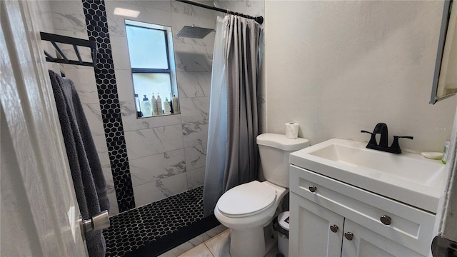 bathroom featuring a tile shower, toilet, and vanity