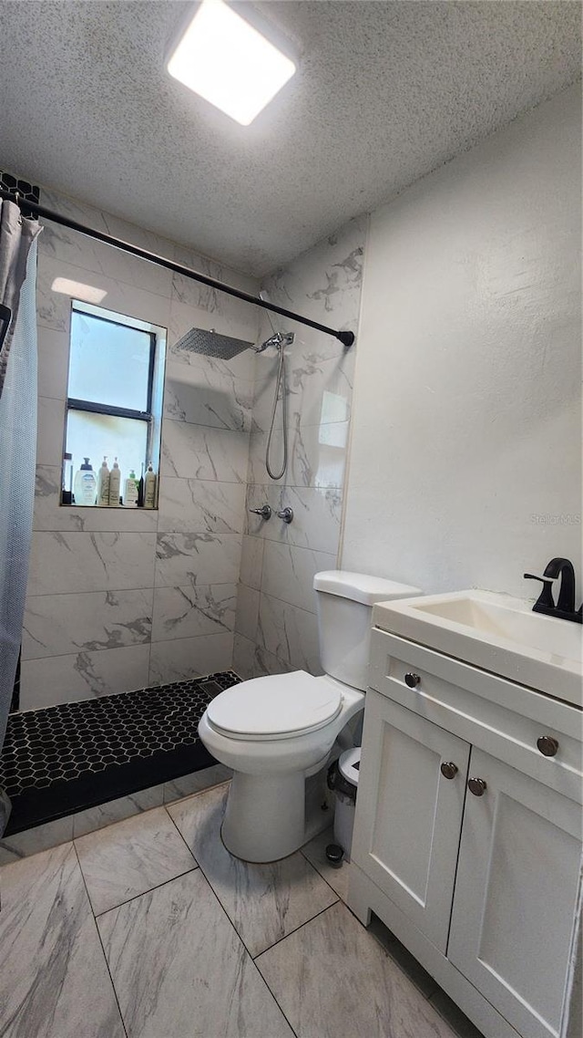 full bathroom featuring marble finish floors, a textured ceiling, tiled shower, toilet, and vanity
