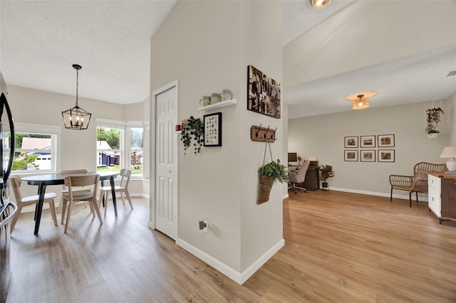 1050 Dees Dr, Oviedo, FL 32765 - interior space featuring baseboards, light wood-type flooring, a chandelier, a textured ceiling, and lofted ceiling