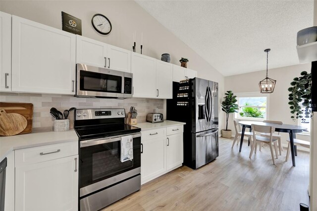 1050 Dees Dr, Oviedo, FL 32765 - kitchen with stainless steel appliances, vaulted ceiling, backsplash, a textured ceiling, and white cabinets