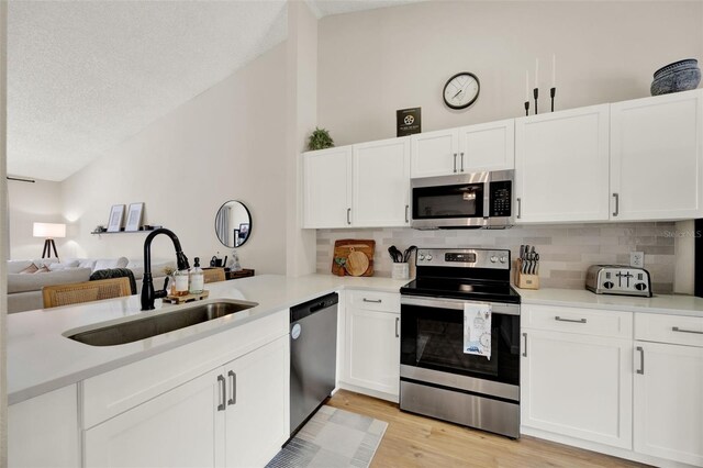 1050 Dees Dr, Oviedo, FL 32765 - kitchen with stainless steel appliances, a sink, lofted ceiling, decorative backsplash, and white cabinetry