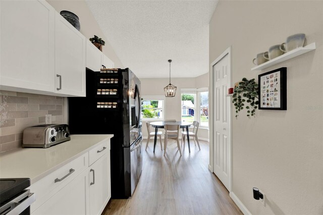 1050 Dees Dr, Oviedo, FL 32765 - kitchen featuring tasteful backsplash, light wood-style floors, white cabinetry, freestanding refrigerator, and a textured ceiling