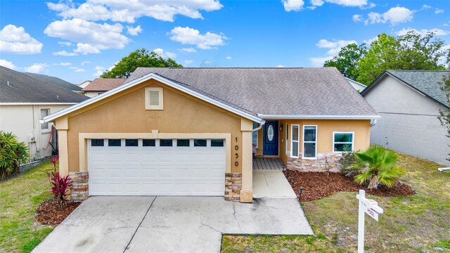 1050 Dees Dr, Oviedo, FL 32765 - view of front of home featuring stone siding, stucco siding, a garage, concrete driveway, and roof with shingles