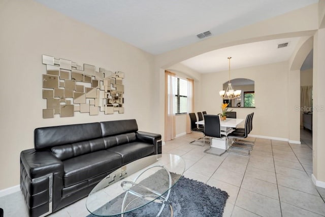 living area with visible vents, baseboards, arched walkways, and a notable chandelier