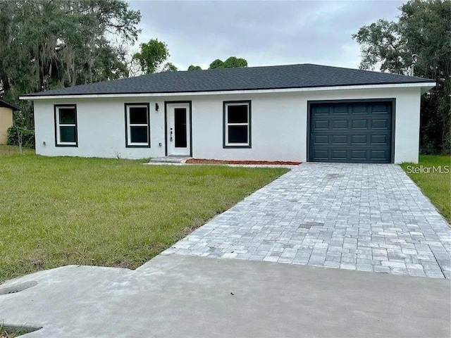 view of front of property featuring a garage, decorative driveway, a front yard, and stucco siding