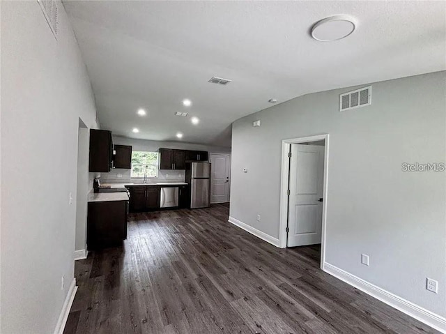 unfurnished living room with dark wood finished floors, a sink, baseboards, lofted ceiling, and recessed lighting