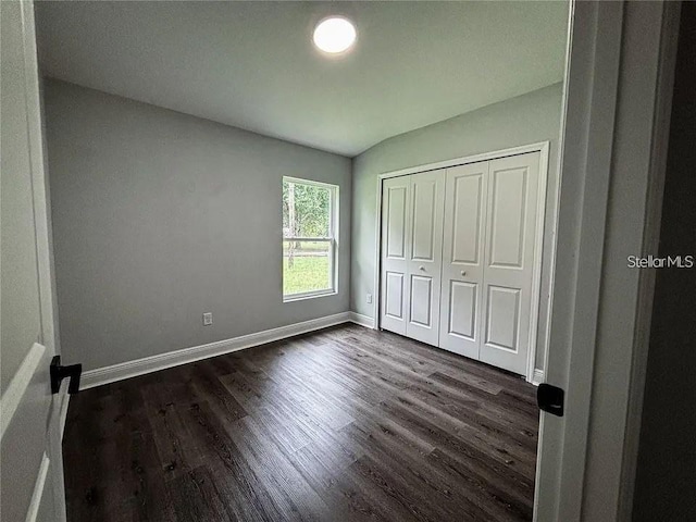 unfurnished bedroom featuring baseboards, dark wood-style floors, and a closet