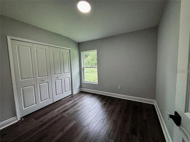 unfurnished bedroom featuring baseboards, dark wood finished floors, and a closet