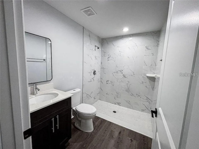 bathroom featuring toilet, vanity, wood finished floors, and a shower stall