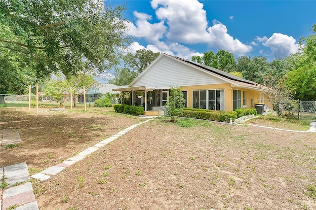 906 Elm Forest Dr, Minneola, FL 34715 - back of house with a sunroom, fence, and roof mounted solar panels