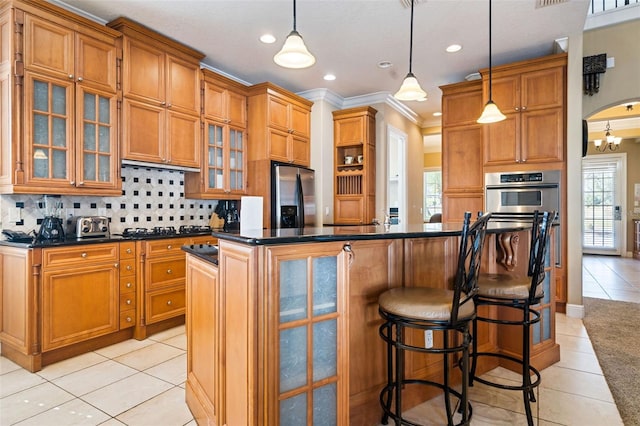 7550 Gathering Dr, Reunion, FL 34747 - kitchen featuring appliances with stainless steel finishes, light tile patterned floors, dark countertops, tasteful backsplash, and crown molding