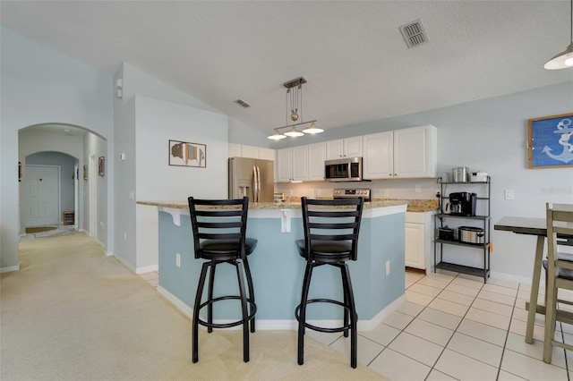 4796 Cumbrian Lakes Dr, Kissimmee, FL 34746 - kitchen with appliances with stainless steel finishes, arched walkways, white cabinets, decorative light fixtures, and a breakfast bar