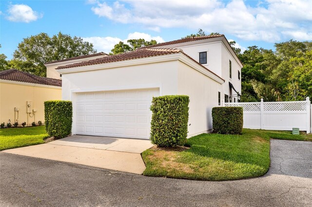 1047 Banks Rose St, Kissimmee, FL 34747 - view of side of property featuring an attached garage, concrete driveway, stucco siding, and a tiled roof