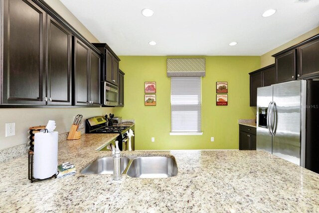 4416 Acorn Ct, Davenport, FL 33837 - kitchen featuring stainless steel appliances, recessed lighting, dark brown cabinets, a sink, and light stone countertops