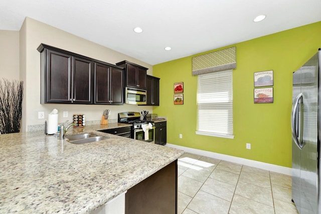 4416 Acorn Ct, Davenport, FL 33837 - kitchen with stainless steel appliances, a sink, baseboards, light stone counters, and dark brown cabinetry