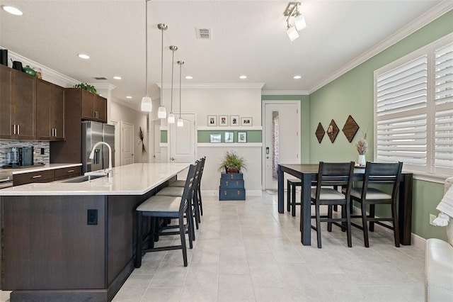 3428 Sagebrush St, Saint Cloud, FL 34773 - kitchen with a sink, stainless steel fridge, dark brown cabinetry, light countertops, and ornamental molding