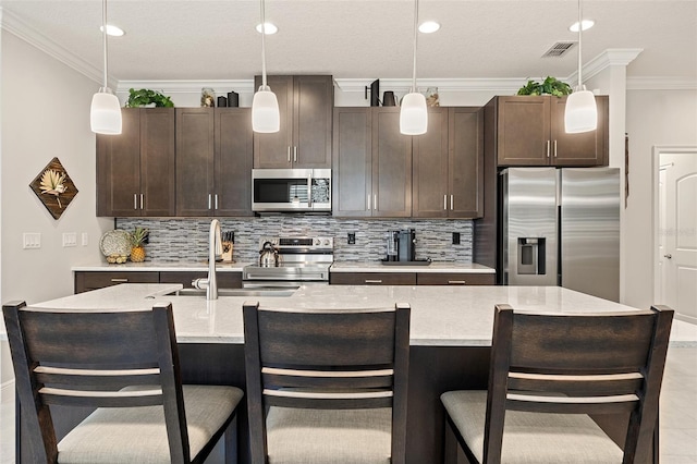 3428 Sagebrush St, Saint Cloud, FL 34773 - kitchen with appliances with stainless steel finishes, dark brown cabinetry, tasteful backsplash, a sink, and a kitchen bar