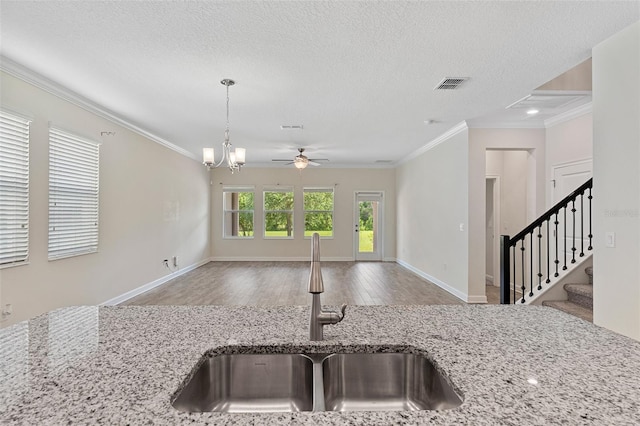 3138 Dark Sky Dr, Saint Cloud, FL 34773 - kitchen featuring a sink, open floor plan, ornamental molding, wood finished floors, and light stone countertops