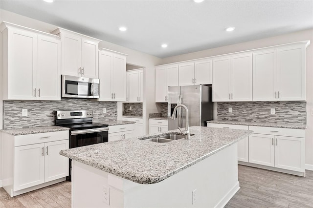 3138 Dark Sky Dr, Saint Cloud, FL 34773 - kitchen featuring appliances with stainless steel finishes, a sink, white cabinetry, a center island with sink, and decorative backsplash