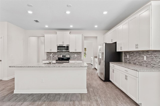 3138 Dark Sky Dr, Saint Cloud, FL 34773 - kitchen featuring stainless steel appliances, a sink, tasteful backsplash, a kitchen island with sink, and white cabinets