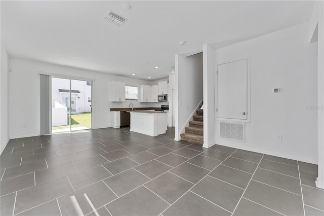 7728 Stone Creek Trl, Kissimmee, FL 34747 - unfurnished living room featuring dark tile patterned floors, stairway, a sink, baseboards, and recessed lighting