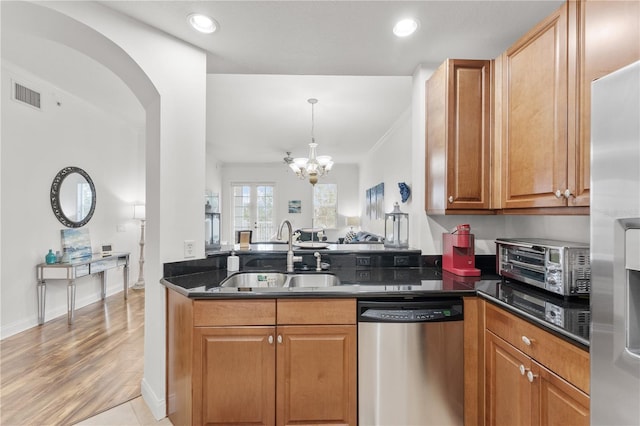 7509 Mourning Dove Cir Unit 303, Reunion, FL 34747 - kitchen featuring appliances with stainless steel finishes, a sink, a chandelier, brown cabinets, and arched walkways