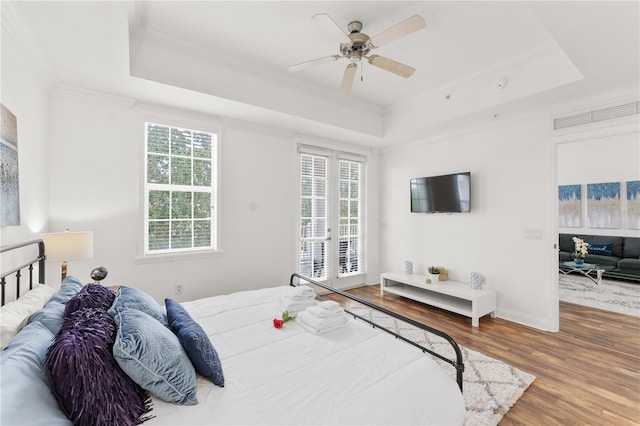 7509 Mourning Dove Cir Unit 303, Reunion, FL 34747 - bedroom featuring a raised ceiling, access to exterior, multiple windows, crown molding, and wood finished floors