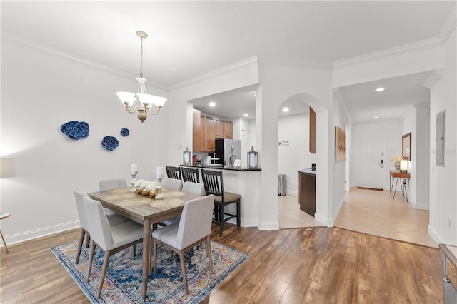 7509 Mourning Dove Cir Unit 303, Reunion, FL 34747 - dining space featuring a chandelier, arched walkways, light wood finished floors, crown molding, and recessed lighting