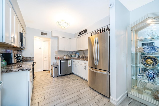 4403 S Semoran Blvd Unit 2, Orlando, FL 32822 - kitchen featuring appliances with stainless steel finishes, white cabinets, baseboards, tasteful backsplash, and light wood-type flooring