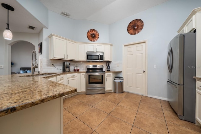 402 Ohio Way, Kissimmee, FL 34759 - kitchen with appliances with stainless steel finishes, a sink, arched walkways, tasteful backsplash, and hanging light fixtures