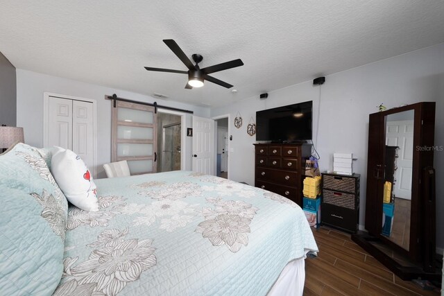 402 Ohio Way, Kissimmee, FL 34759 - bedroom with wood finish floors, a barn door, a closet, a textured ceiling, and a ceiling fan